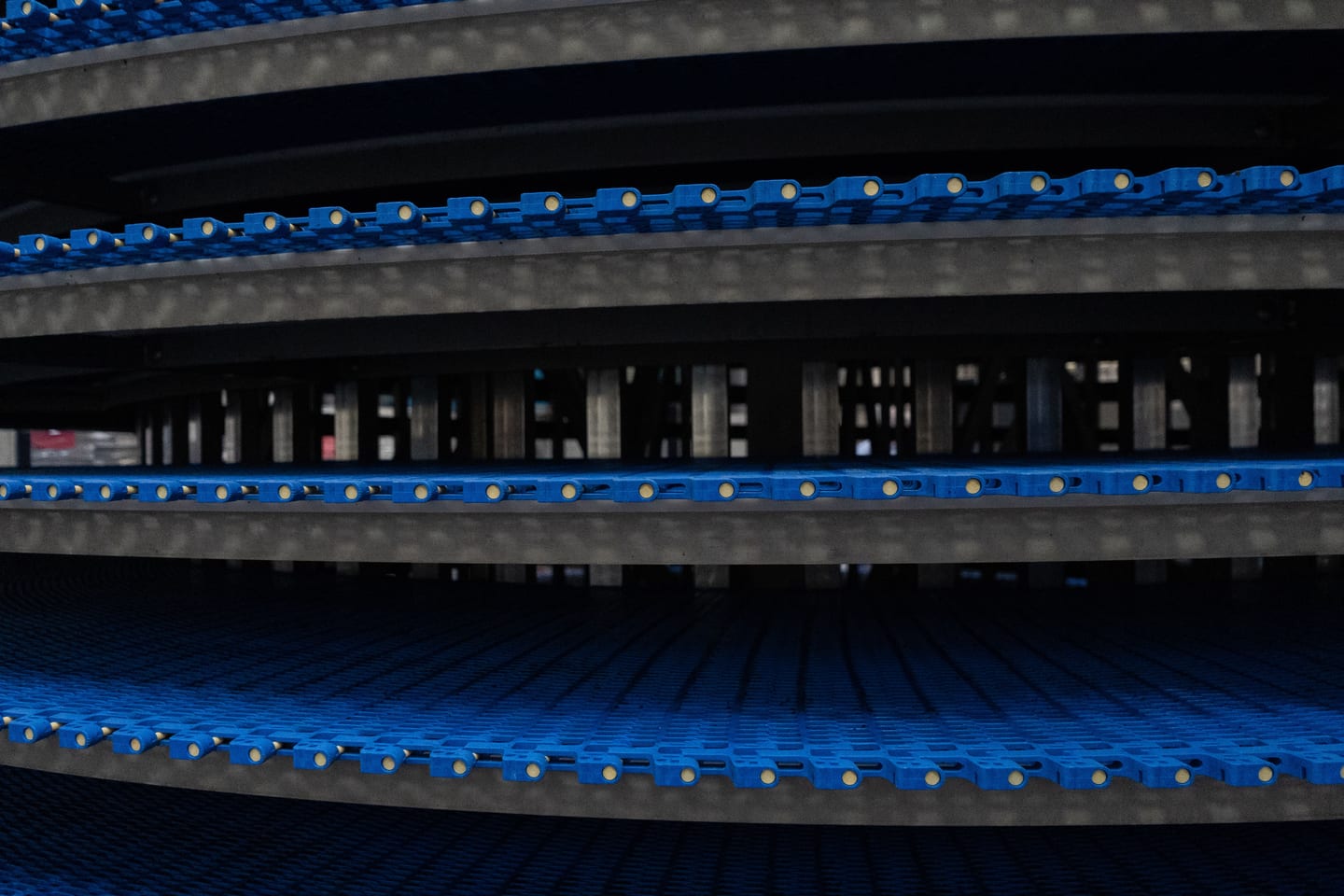Close view of blue conveyor chain through a cooling assembly