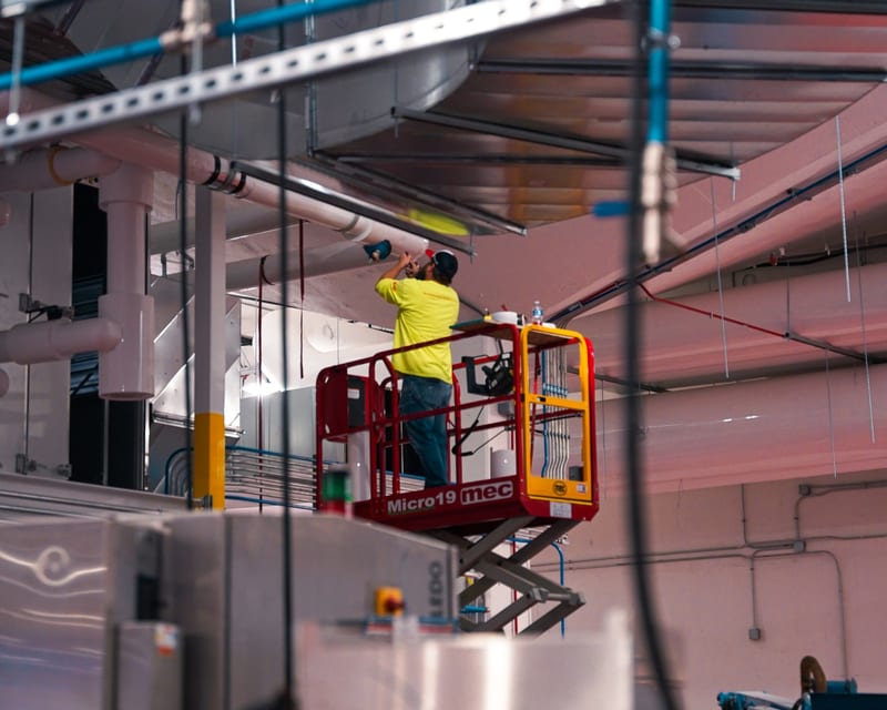 THG technician on a scissor lift working on overhead ductwork during an installation