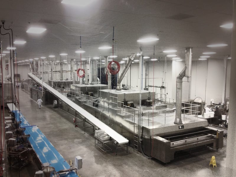 Industrial oven and adjoining conveyors viewed across a bakery production area